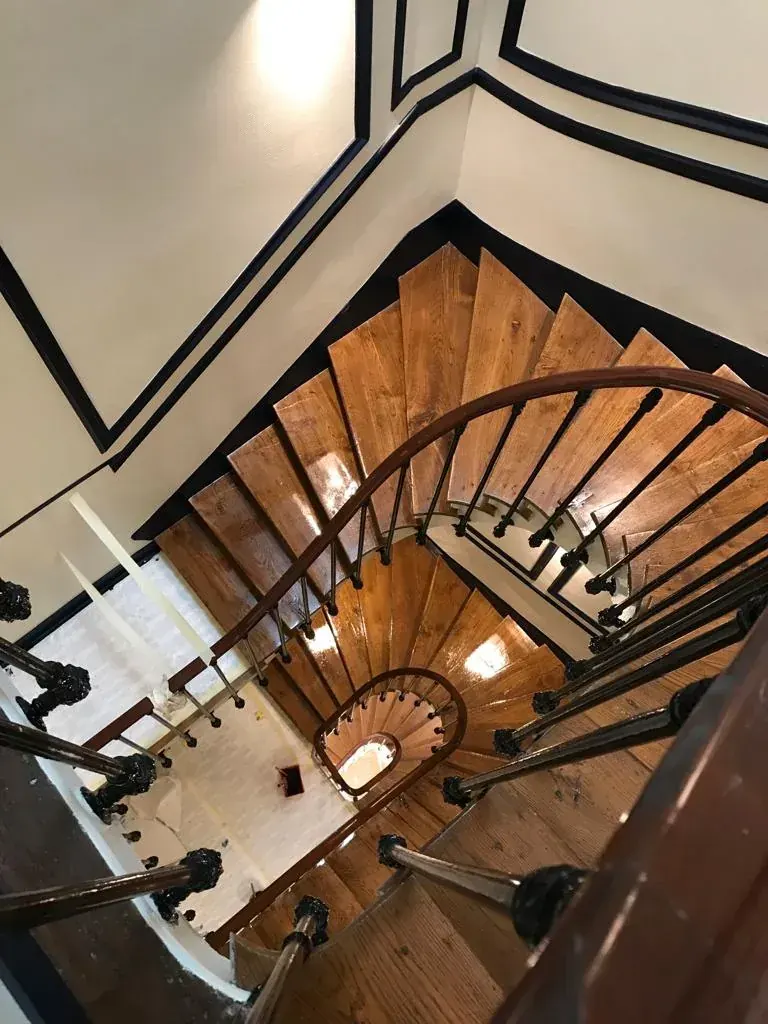 Escalier colimaçon rénové Paris — parquet chêne, ferronnerie noire