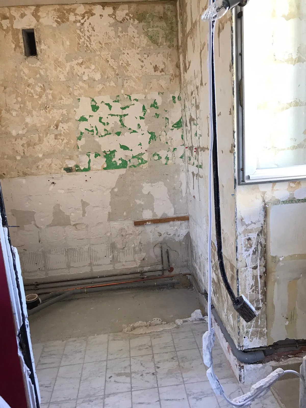 Salle d'eau mise à nu avant rénovation : murs décapés et réseaux apparents, appartement du 14e arrondissement de Paris