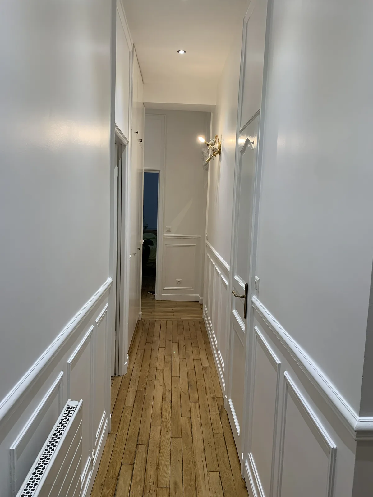 Couloir haussmannien avec boiseries et portes repeintes en blanc après travaux de peinture, Paris 16e