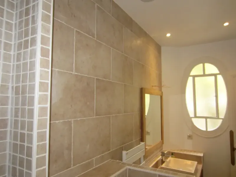 Salle de bain Levallois — travertin, fenêtre ovale